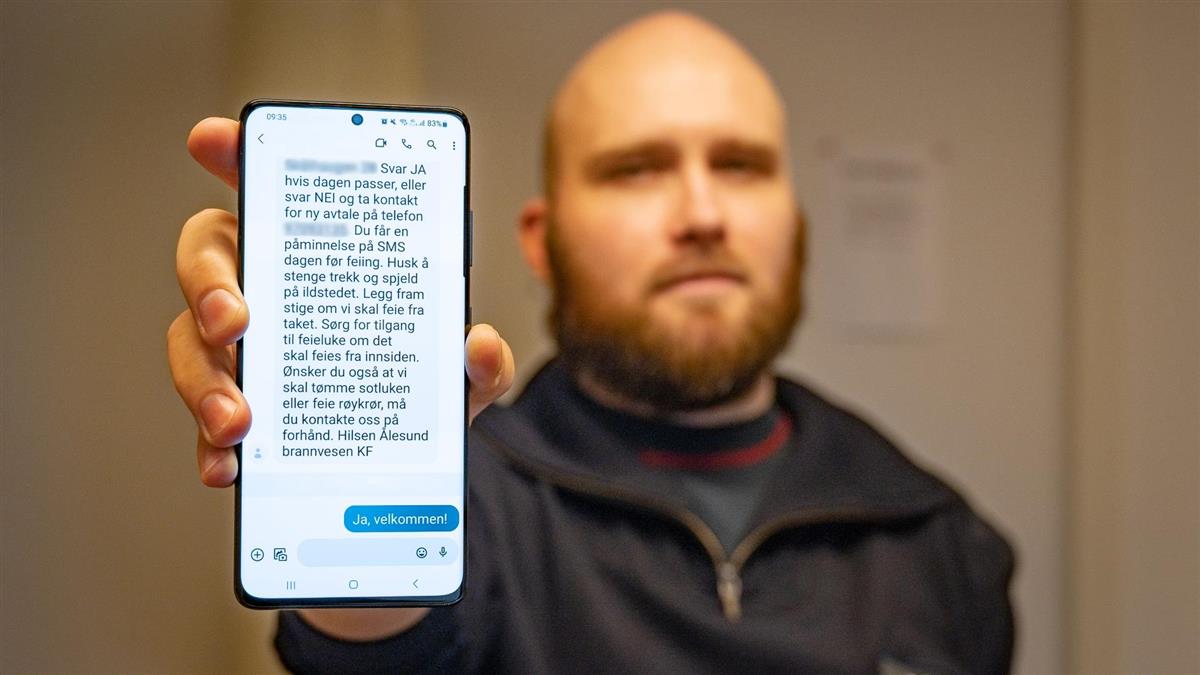Feier viser mobiltelefon med SMS for varsling av feiing - Klikk for stort bilde